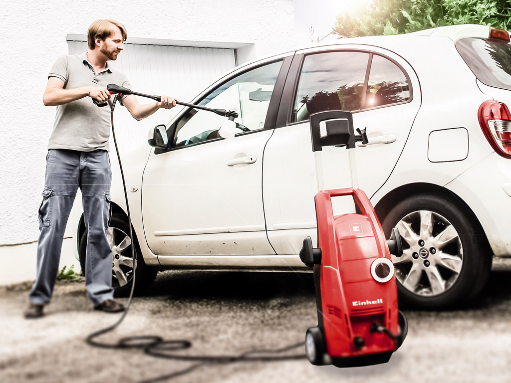 a man cleans his car with a pressure washer