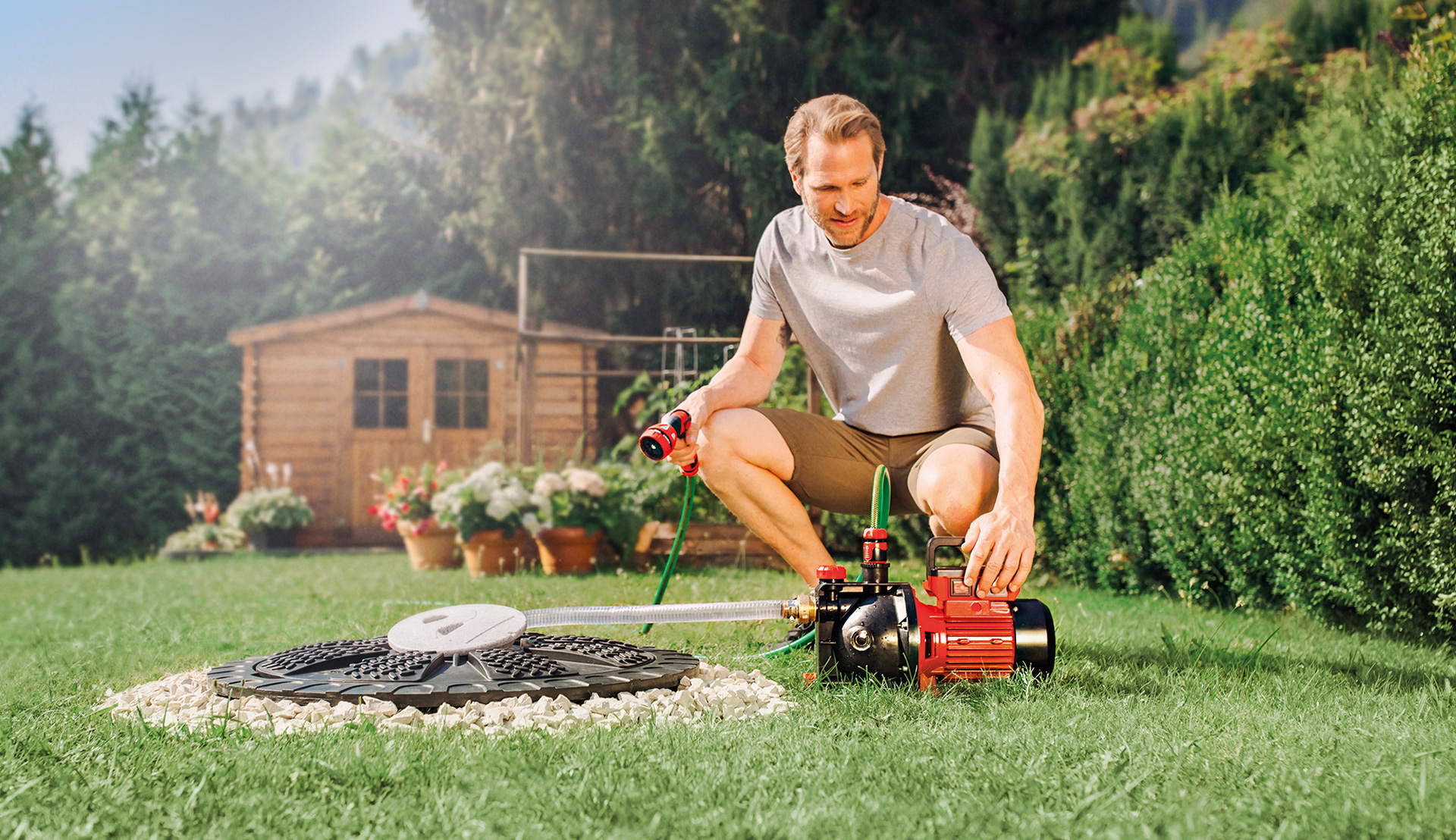 A man switches on an Einhell garden pump to water his garden.