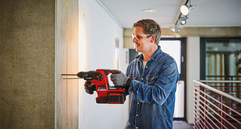 man using a cordless rotary hammer on a wall