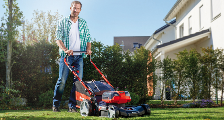 a man mows his garden with a lawn mower